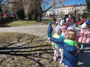 Grupa dzieci jest na spacerze w parku. Poszukują oznak wiosny.
