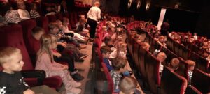 Dzieci siedzą w teatrze i czekają na spektakt