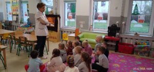 Dzieci siedzą na dywnie u słuchają ciekawostek o pracy Pani pielęgniarki 