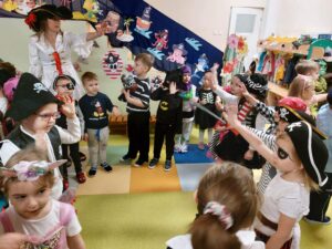 Dzieci wraz z nauczycielami tańczą w kółeczku przebrane za piratki i pratów 