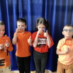 Dzieci ubrane na pomarańczowo piją sok marchewkowy