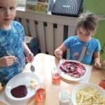 Dwoje dzieci przy stolikach spożywa posiłek w kolorze niebieskim