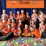 grupa dzieci ubrana na pomarańczowo trzyma wykonane pomarańczowe lody