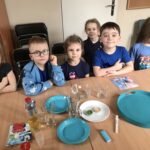 Grupa dzieci siedzi przy stolikach. Wykonują doświadczenia z kolorem niebieskim