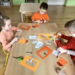 Grupa dzieci wykonuje lody pomarańczowe z papieru