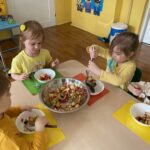 Dzieci zjadają na podwieczorek przygotowaną przez siebie sałatkę owocową.