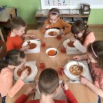 Dzieci spożywają obiad w kolorze pomarańczowym