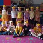 Grupa dzieci ubrana w kolorze żółtym. Na głowach mają opaski w tym kolorze