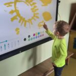 Chłopiec rysuje słoneczko na tablicy multimedialnej