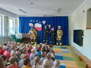 Przedszkolaki słuchają jak opowiadają o sobie strażacy 